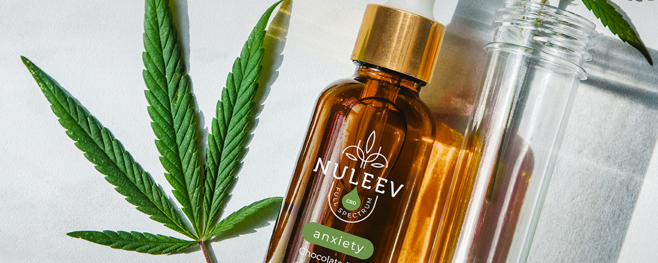 Nuleev branded dropper bottle flat lay with cannabis leaf and vial
