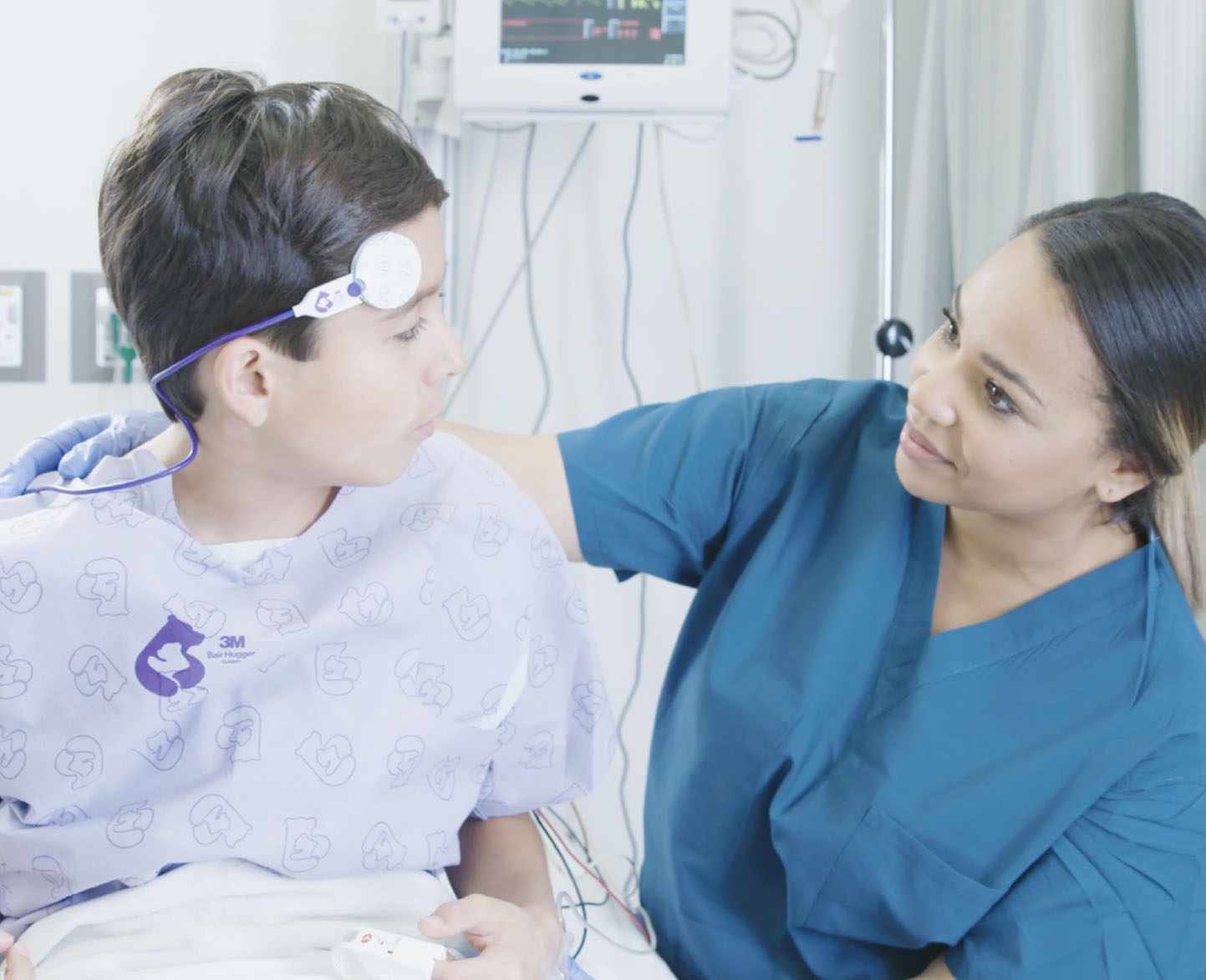 female medical professional listens to young patient using 3M branded medical device